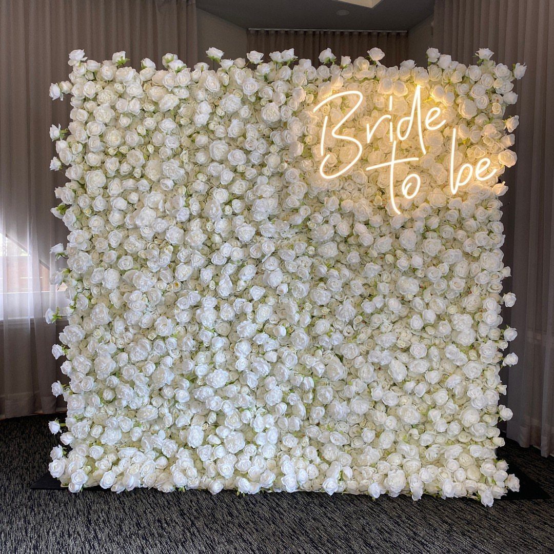 White rose flower wall backdrop with a glowing Bride to be neon sign