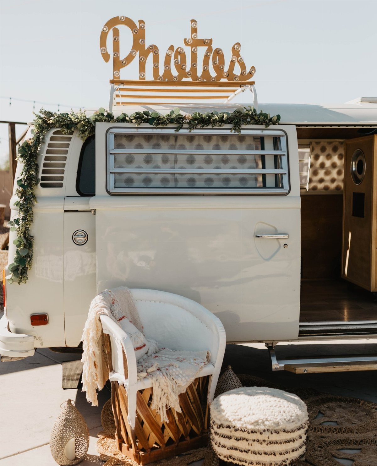 White vintage VW van photo booth with marquee sign and bohemian seating area.