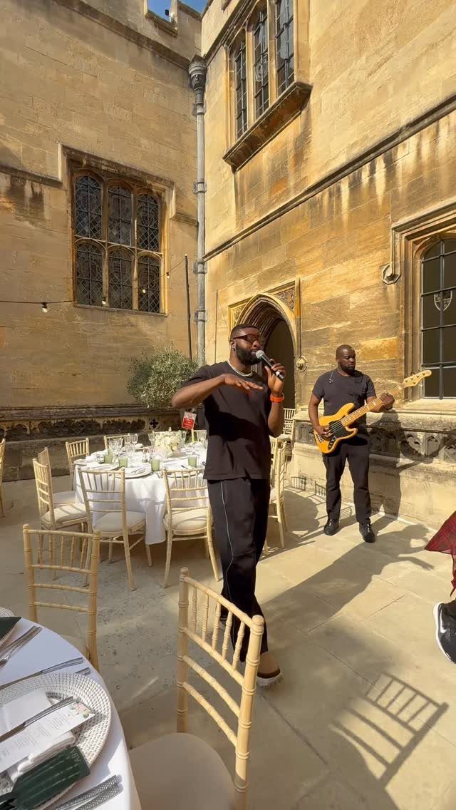 Musicians performing with a microphone and electric guitar in a stone courtyard setting