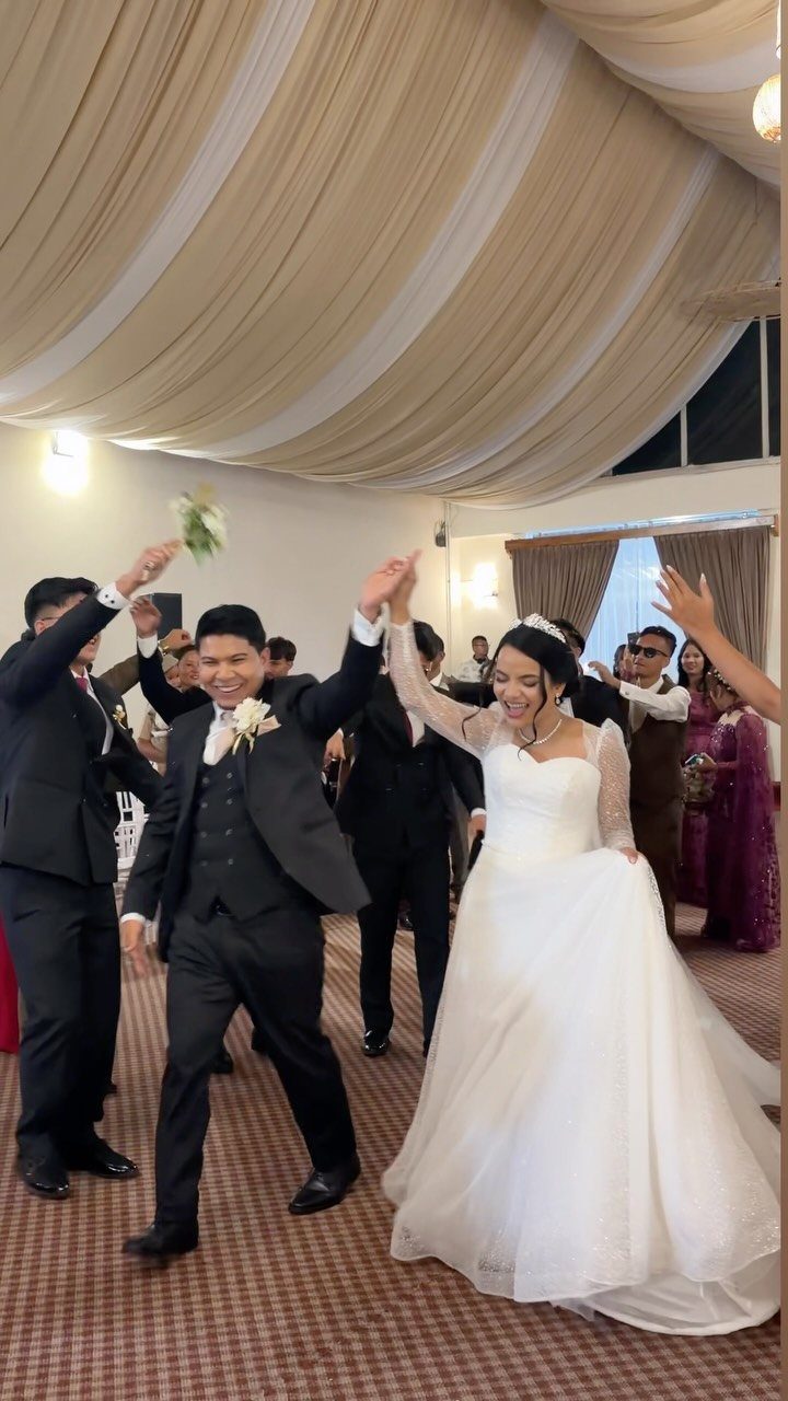 Bride and groom dancing joyfully during their wedding party entrance with cheering guests.