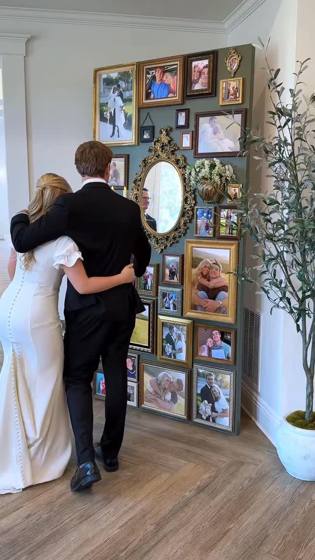 Bride and groom looking at a green photo board with framed wedding pictures.