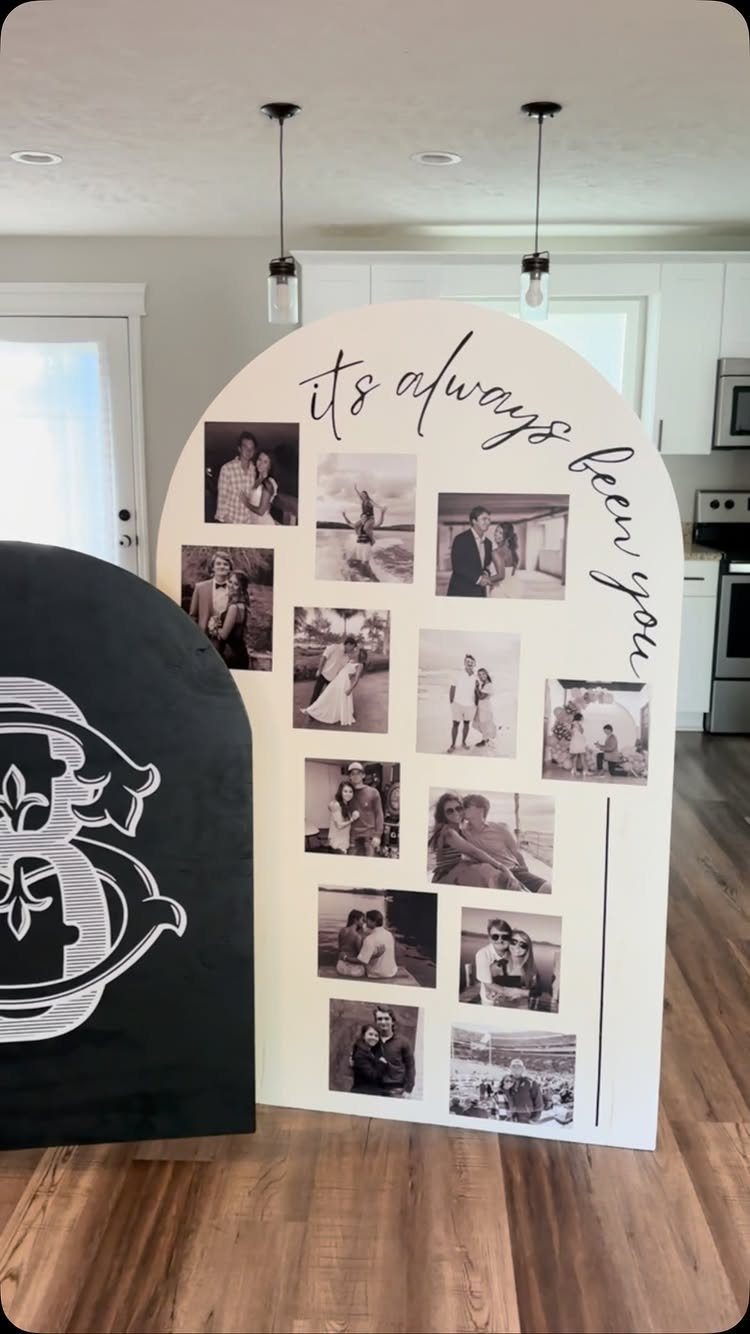 White arched backdrop board decorated with black and white photos and cursive text.