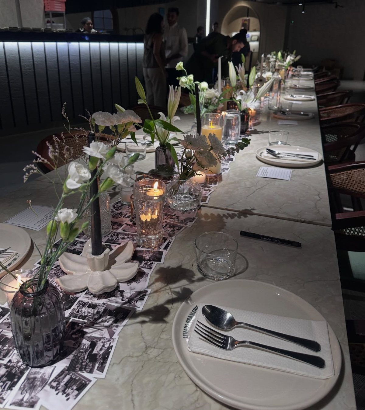 Marble dining table with a photo runner, white flowers, and lit candles