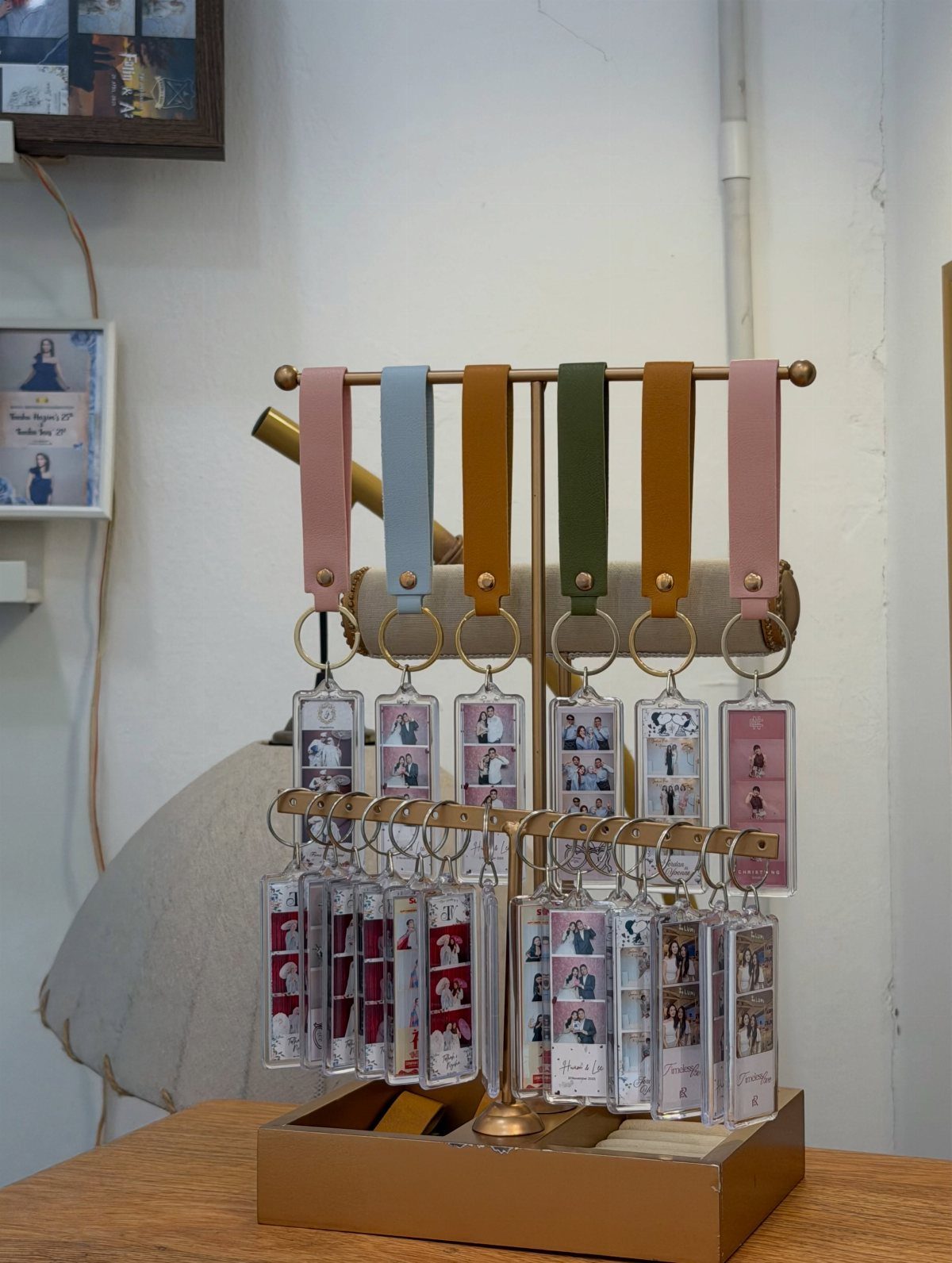 Wedding photo booth strips encased in acrylic keychains on a gold display stand