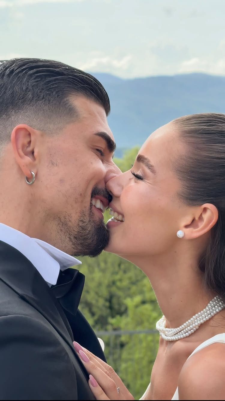 Bride and groom smiling with noses touching in a close-up outdoor portrait.