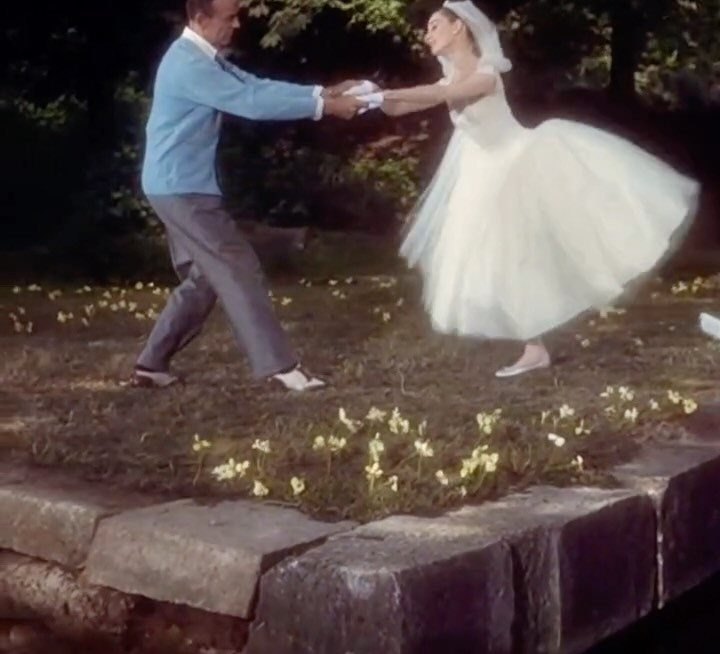 Bride in a full white dress dancing with groom in a garden setting