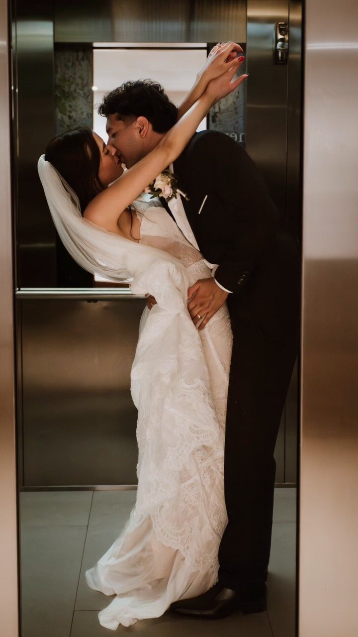Bride and groom kissing in a dip inside a metallic elevator