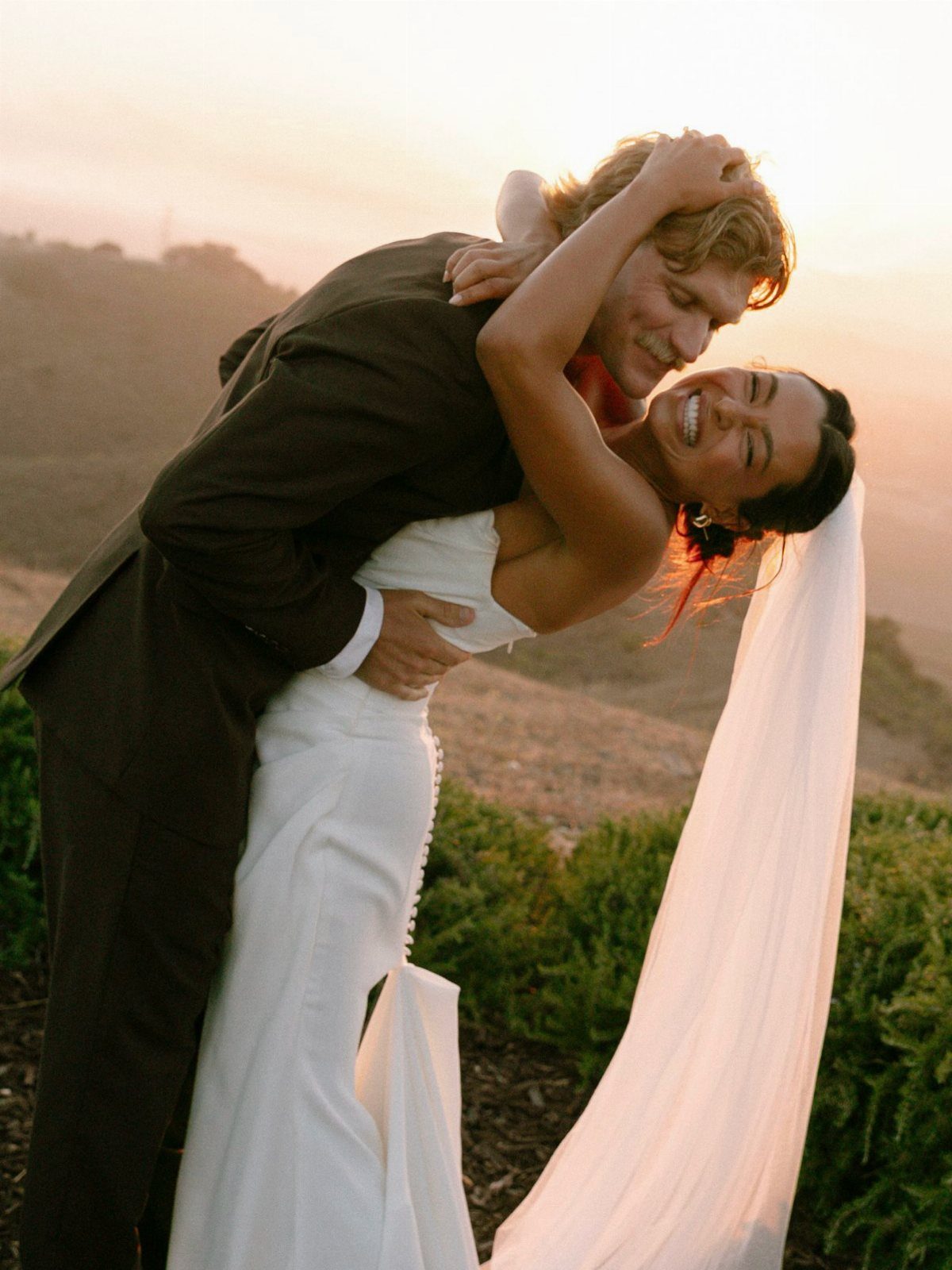 Bride and groom embracing in a dip pose during a sunset outdoor wedding.