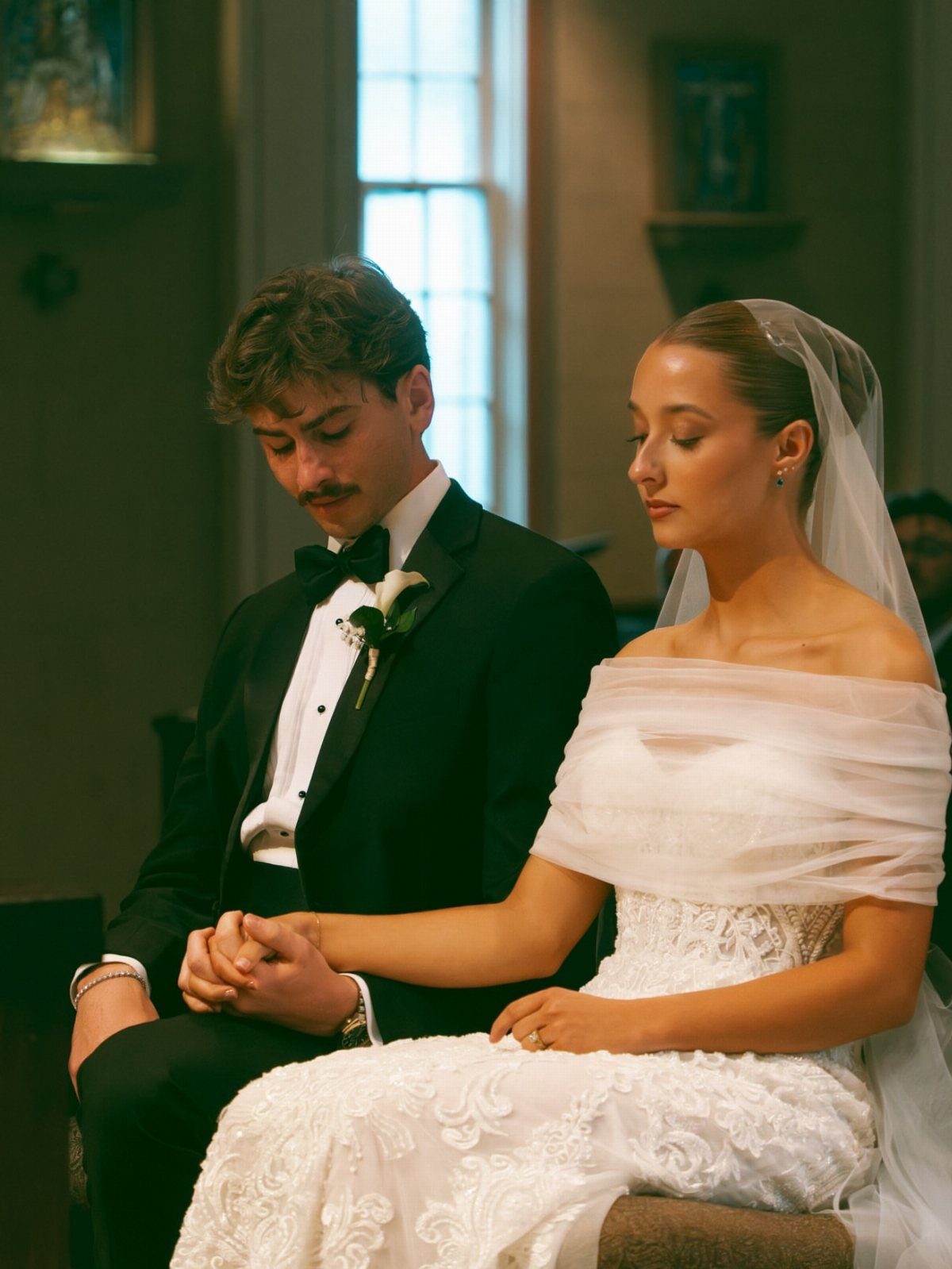 Bride and groom sitting together and holding hands during their wedding ceremony.