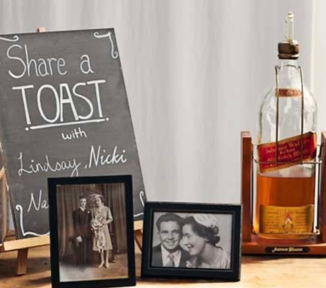 Vintage wedding photos and a chalkboard sign on a wooden table with liquor.