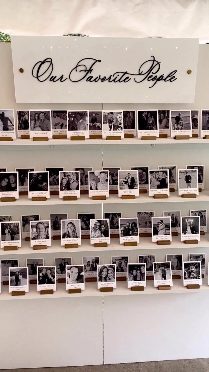 White tiered shelf displaying black and white guest photos with wooden stands.