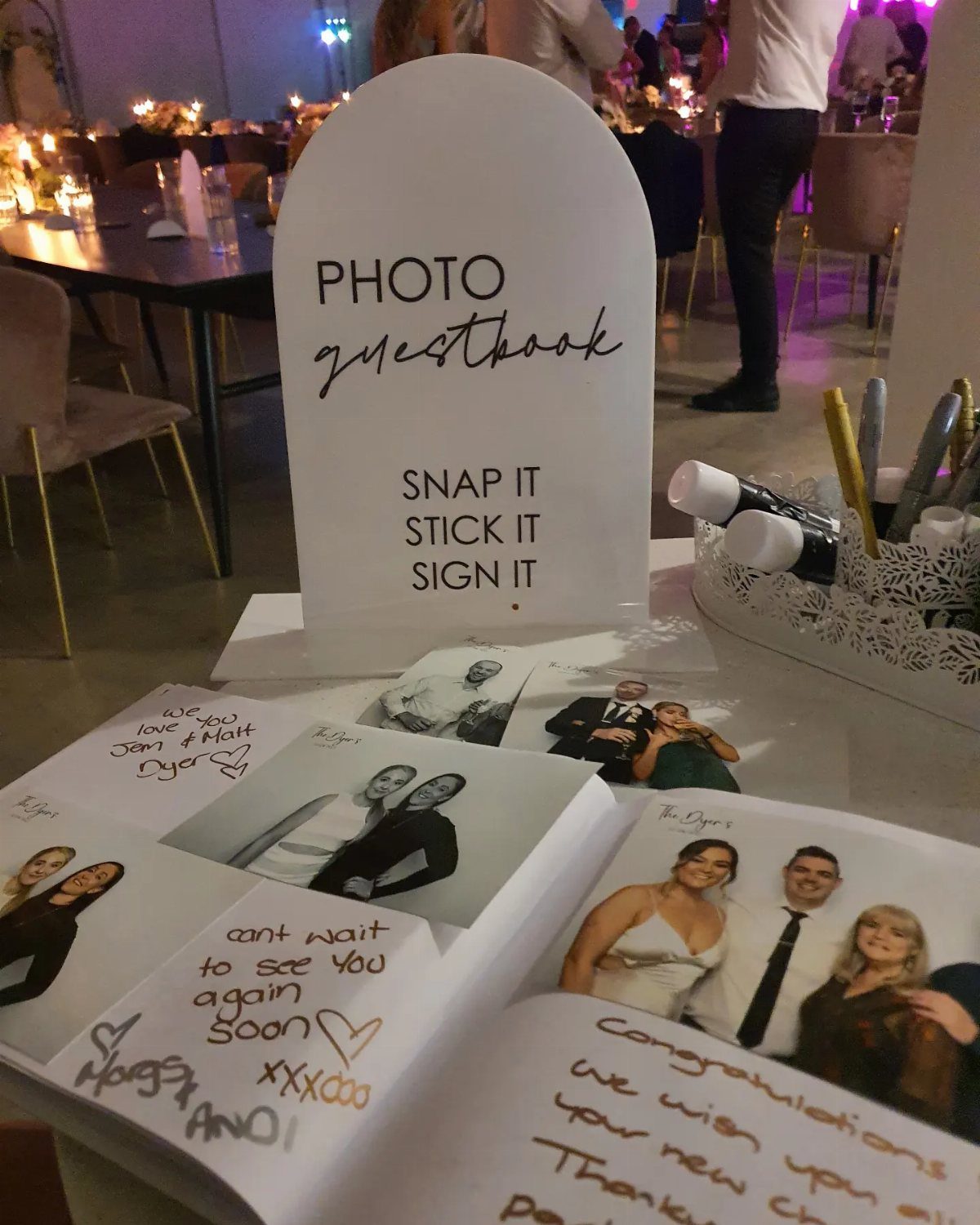 Photo guestbook sign and open album with instant photos and handwritten messages.