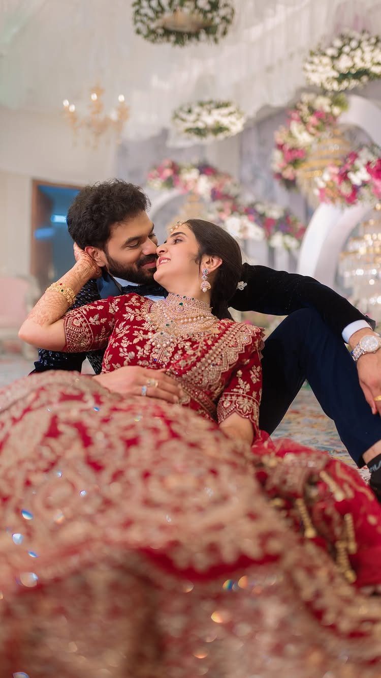 Couple in Indian wedding attire gazing affectionately at each other in a decorated setting