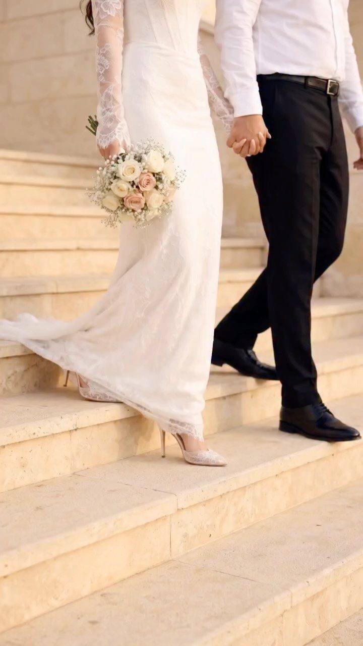 Bride and groom walking hand in hand down stone stairs during wedding.
