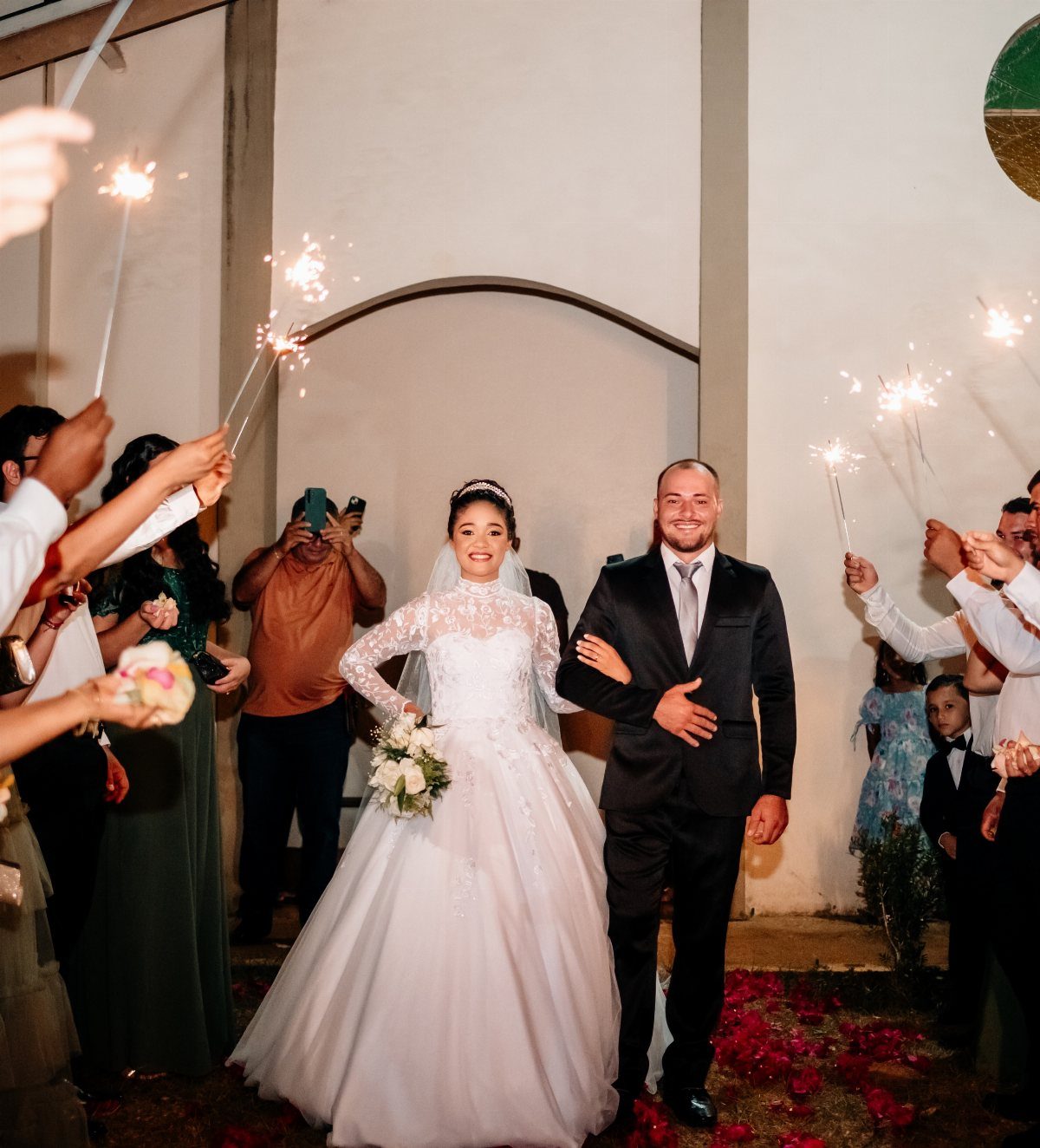 Bride and groom walking through a crowd of guests holding lit sparklers