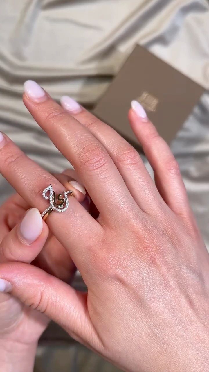 Diamond engagement ring and wedding band on a hand with pink nails.