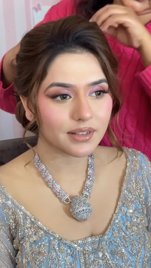 Woman with professional makeup and styled hair wearing a blue embroidered dress